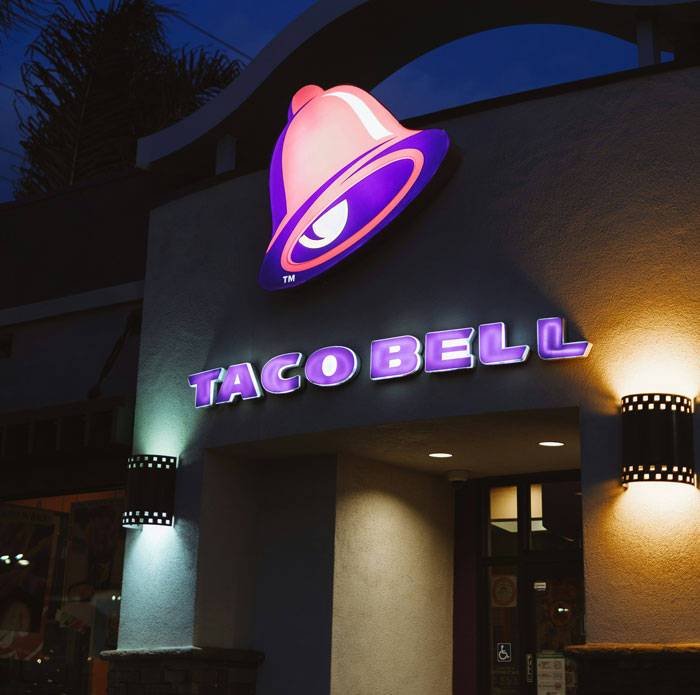 Taco Bell restaurant exterior at night with illuminated sign under an archway highlighting insane therapy revelations theme.