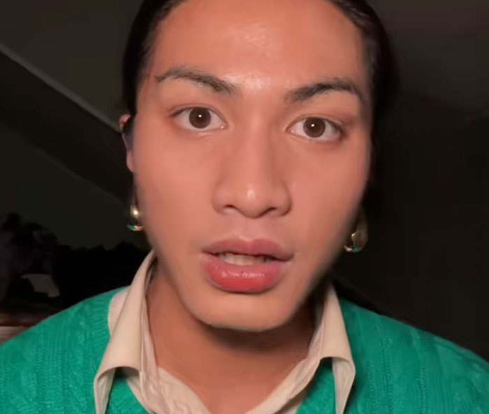 Young person wearing a green sweater and earrings sharing safe driving facts for drivers in an indoor setting.