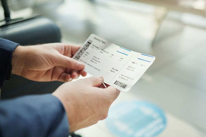 Passenger holding a plane ticket in an airport setting, illustrating entitled plane passenger cutting cue scenario. Passenger holding a plane ticket in an airport setting, illustrating entitled plane passenger cutting cue scenario.
