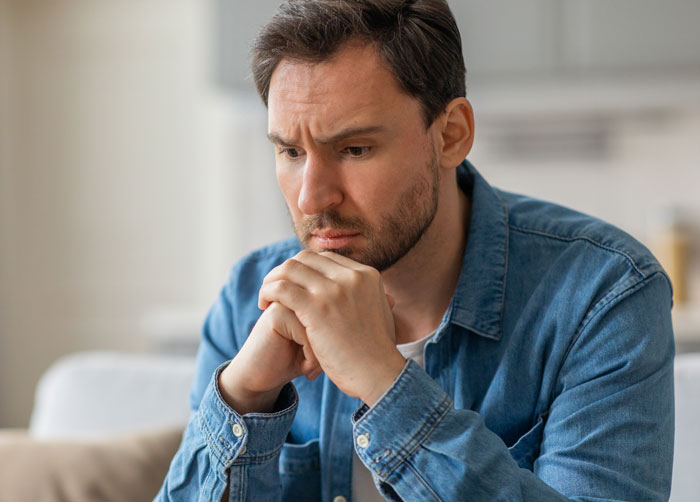 Man looking distressed and contemplative after unexpected investigation results from private investigator about partner.