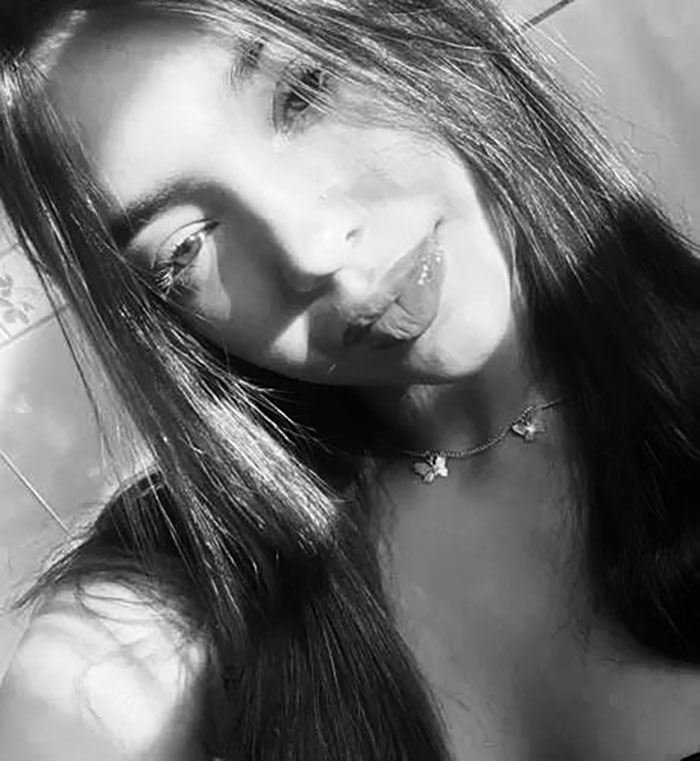 Black and white portrait of a teenage girl with long hair and a butterfly necklace, related to teen loses life after eating cake.