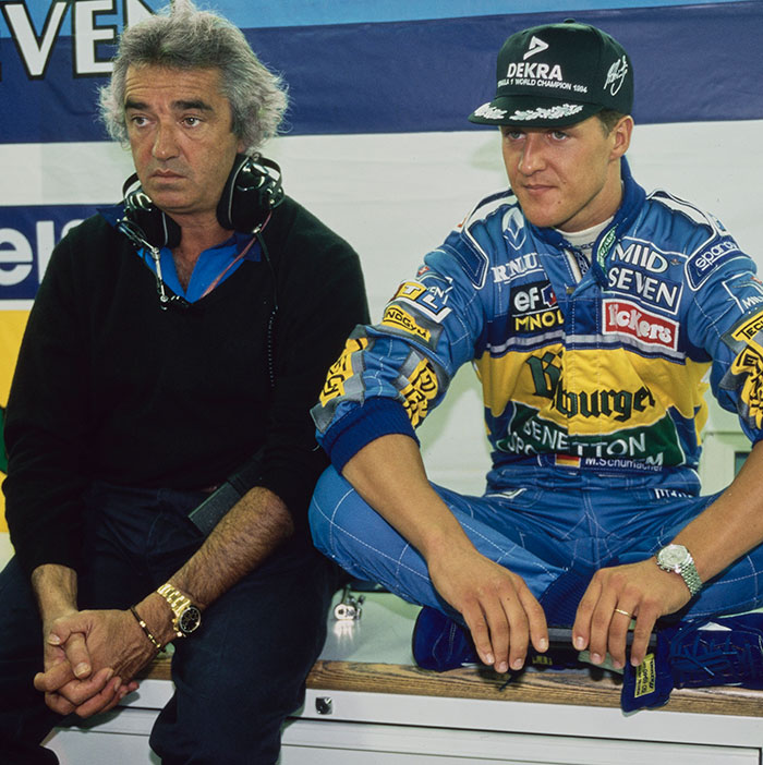 Michael Schumacher in racing suit with former boss wearing headphones, an emotional moment in F1 legend's health update.