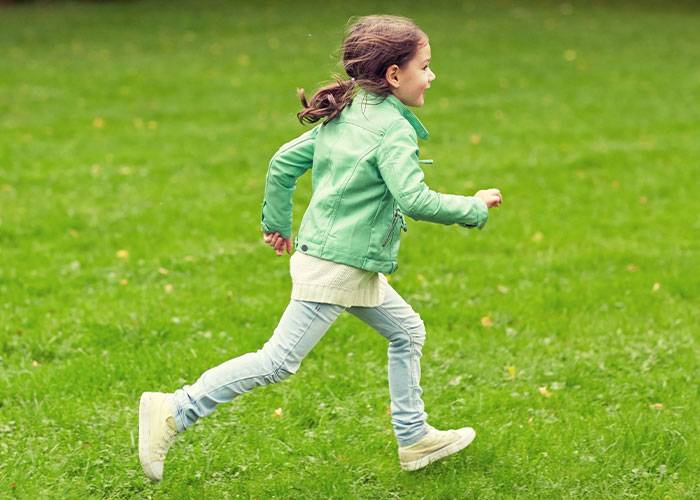 Young girl running joyfully on green grass, illustrating innocence contrasted with creepy facts that might get stuck in your brain forever.