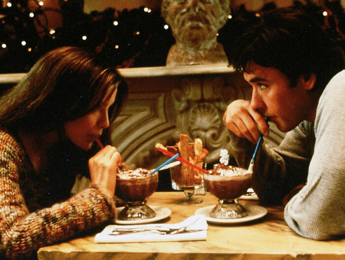 Couple sharing drinks at a table symbolizing romantic but toxic relationships in popular movies like The Notebook.