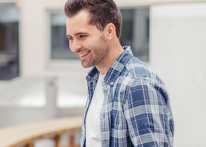 Smiling man in a blue plaid shirt outdoors, representing unhinged things men have said about women's looks in public.