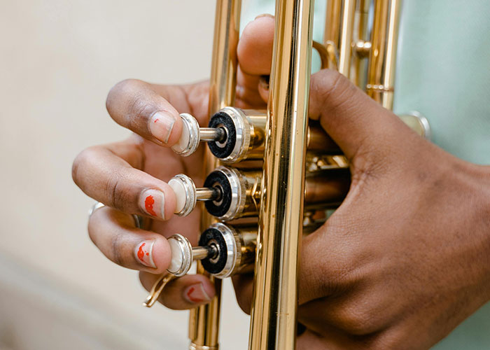 Close-up of hands pressing trumpet valves, illustrating dedication and teamwork in a musical performance moment.