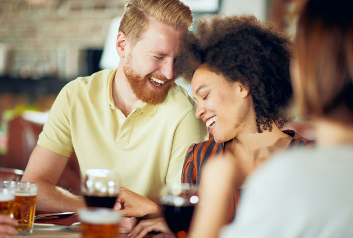 Couple laughing and enjoying drinks together, illustrating common toxic dating trends people weirdly accept as normal.