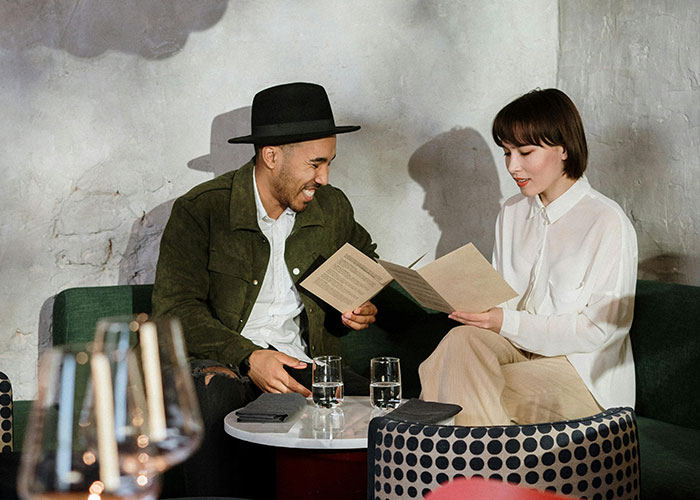 Couple awkwardly holding menus during a tense date at a small café, capturing the essence of painful and awkward dates.