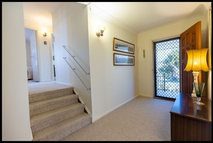 Carpeted indoor stairs with low handrails in a narrow hallway, illustrating a potential hazardous death stairs design.