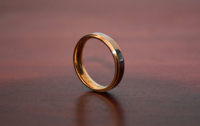 Close-up of a gold ring on a wooden surface symbolizing commitment and personal secrets related to paying for college.
