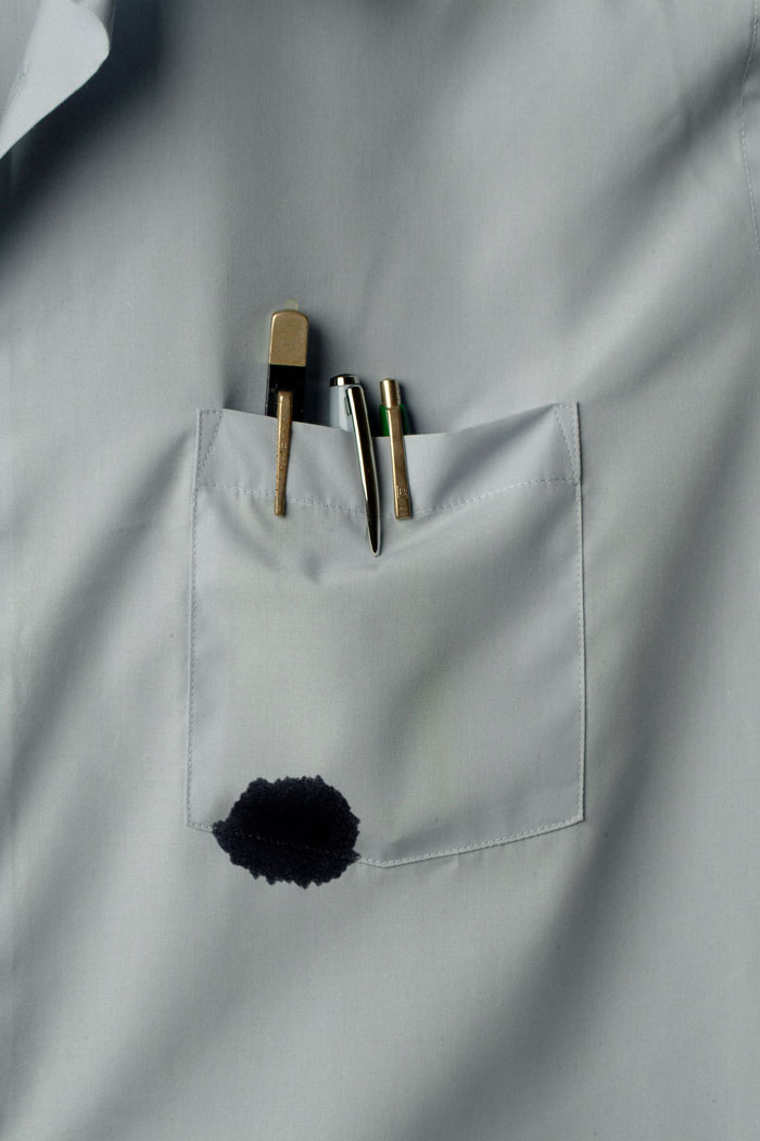 Grey shirt pocket with pens and a dark ink stain symbolizing old wives tales home remedy for stain removal.