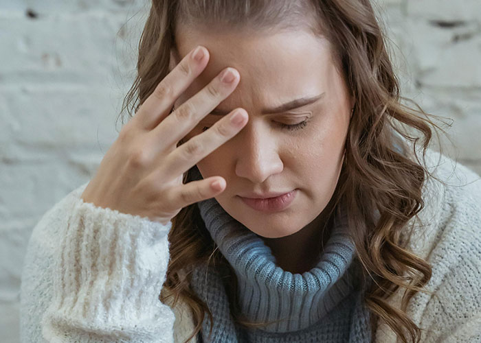 Woman looking stressed and thoughtful, wearing a gray turtleneck and white sweater in an indoor setting. Woman looking stressed and thoughtful, wearing a gray turtleneck and white sweater in an indoor setting.