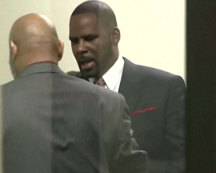 Rapper R Kelly in a dark suit speaking to another man in a courtroom setting, related to alleged prison overdose. Rapper R Kelly in a dark suit speaking to another man in a courtroom setting, related to alleged prison overdose.
