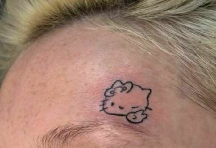 Small, poorly executed Hello Kitty tattoo on a person's forehead, an example of hilariously bad tattoos inkshaming.