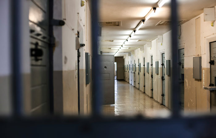 Dimly lit corridor of a prison with rows of closed cell doors, representing one of the scariest places around the world.