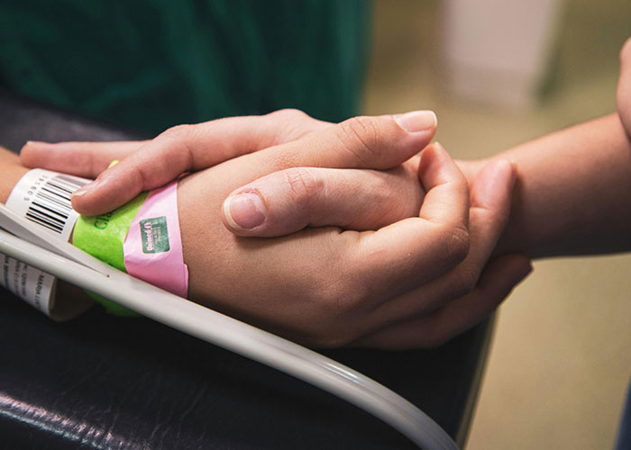 Two hands tightly holding each other inside a birthing room, capturing dads' real experience during childbirth.