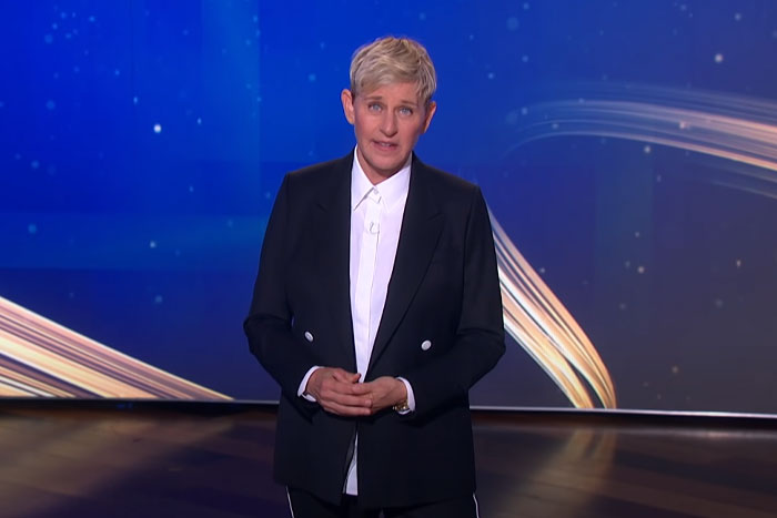 Television star in black suit speaking on stage, representing stars who left Hollywood and found new homes abroad.