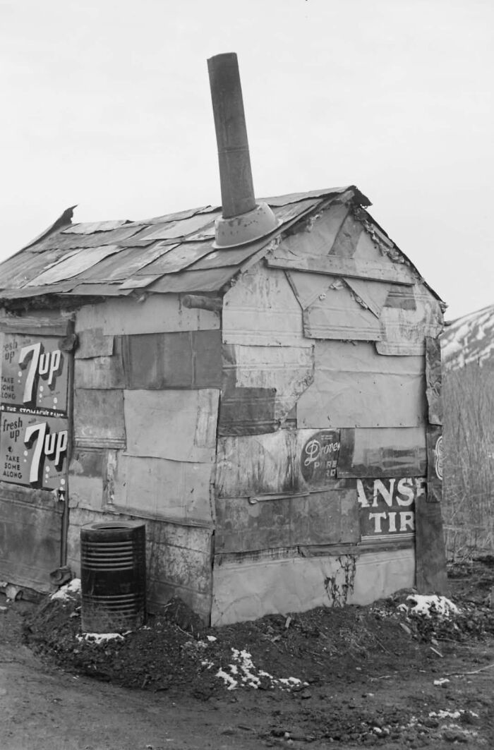 Black and white photo of a ramshackle shack made from scrap materials, illustrating fascinating historical photos impact on perception.