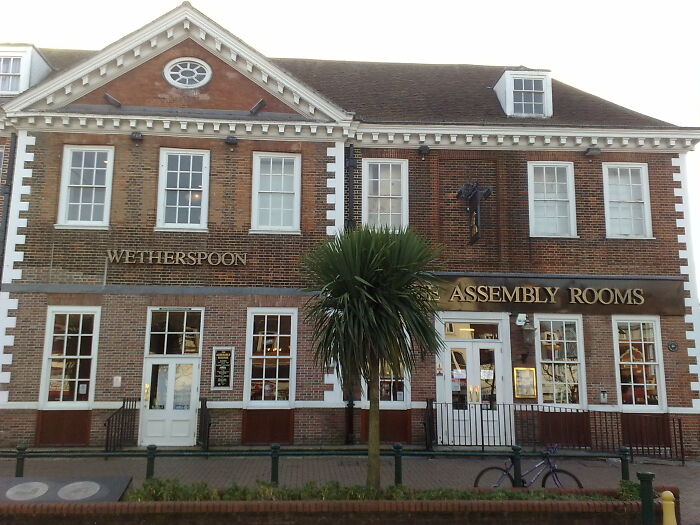 Historic UK pub and assembly rooms building with classic brick facade and palm tree in front, reflecting UK culture and community.