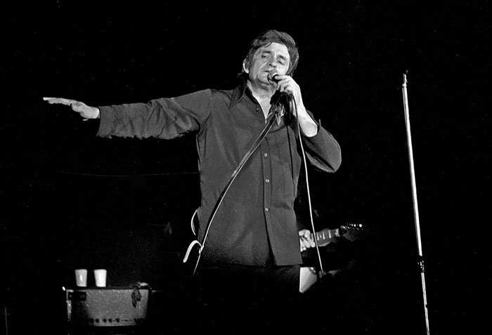 Black and white photo of a famous person performing on stage, illustrating famous people who did evil things.