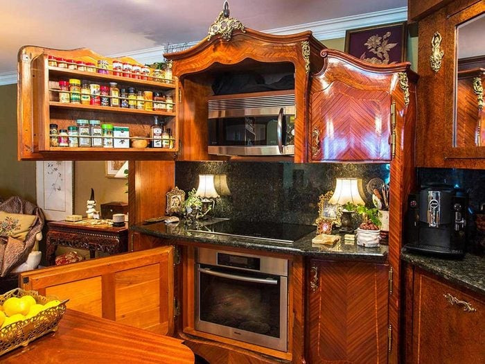 Ornate wooden kitchen cabinets with built-in microwave and oven in an unhinged real estate listing.