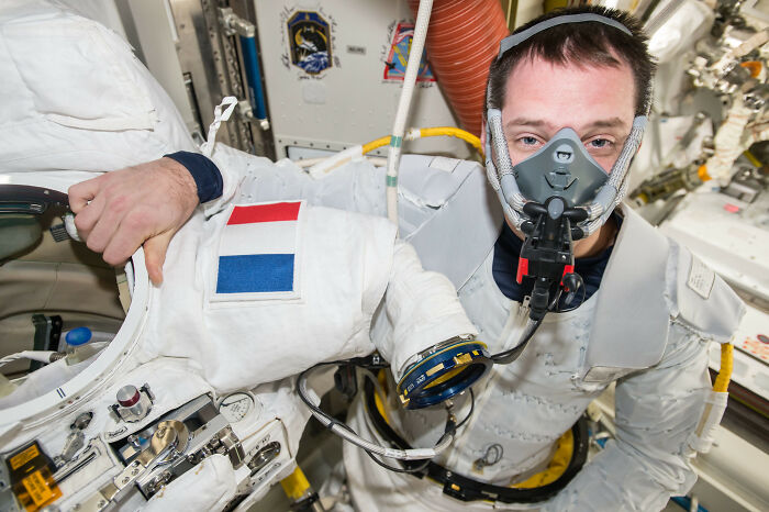 Astronaut inside spacecraft wearing a space suit and oxygen mask showing intriguing and bizarre astronaut facts.