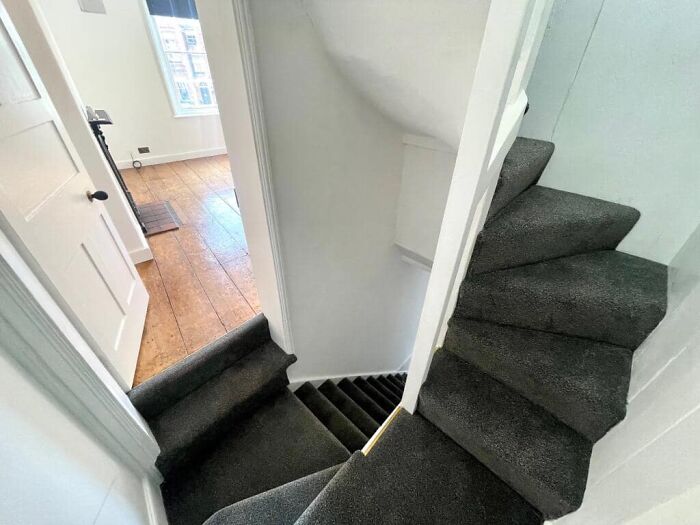 Narrow and steep carpeted stairs with sharp turns, illustrating a dangerous death stairs design inside a modern home.