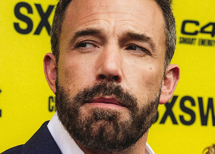 Close-up of a bearded man in a dark suit at an event, illustrating what celebrities were doing before fame found them.