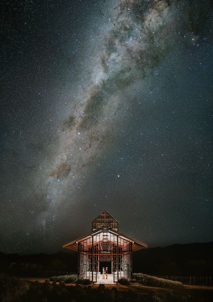 Couple holding hands inside an illuminated chapel under a starry night sky in unforgettable wedding photos.