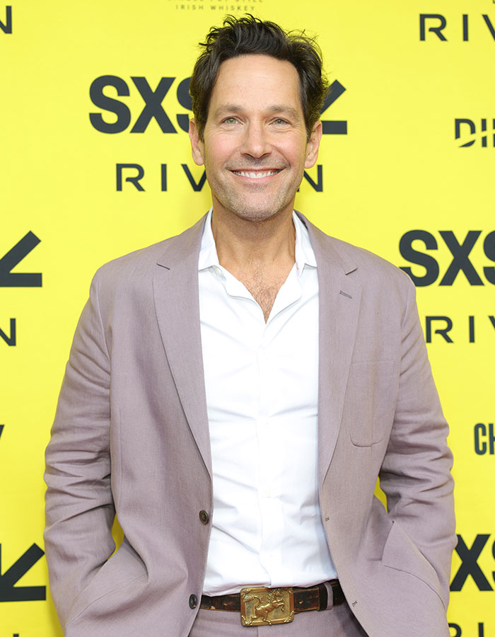 Man in a light purple suit and white shirt smiling at a celebrity event showcasing celebrities who look way younger.