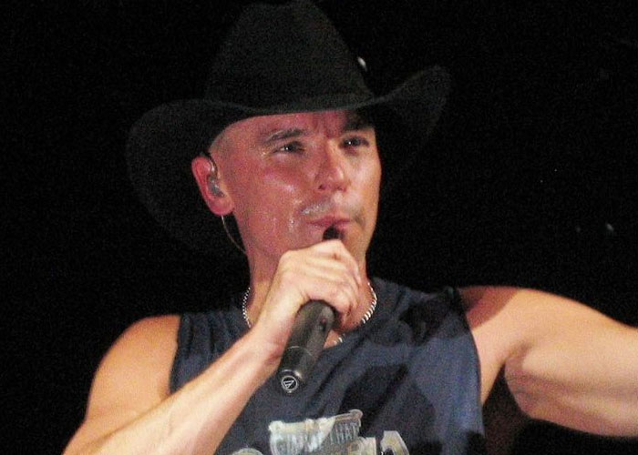 Country singer performing on stage wearing a black cowboy hat, representing celebrities before fame found them.