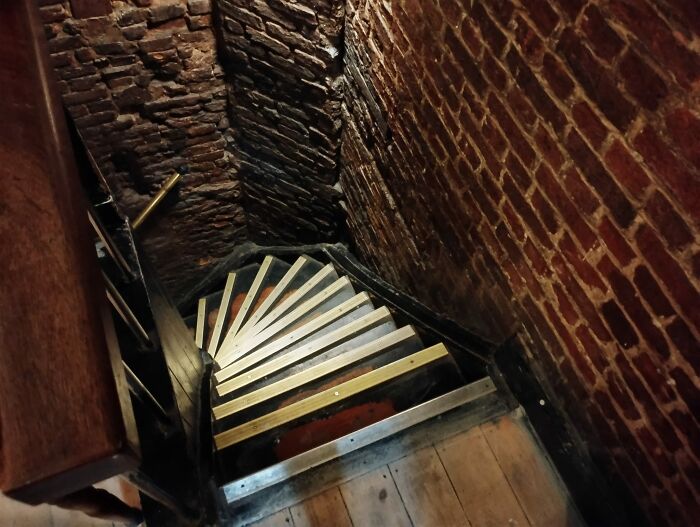 Narrow, steep death stairs with wooden steps and brick walls creating a hazardous and unsafe staircase option.
