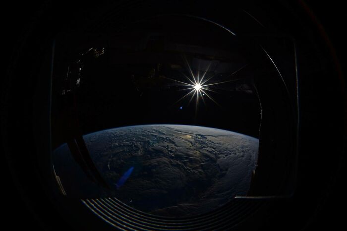 View of Earth from space window with sun flare, illustrating intriguing and bizarre astronaut facts from orbit.
