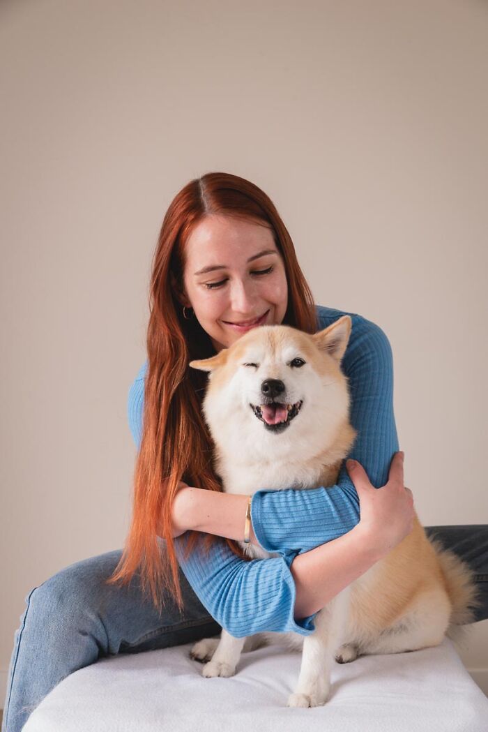 Woman with red hair hugging a happy Shiba Inu dog, one eye winking, showcasing one of the best dog photos.