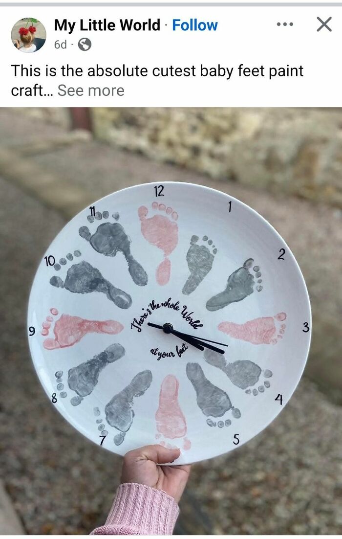 Hand holding a baby feet paint craft clock with pink and gray footprints arranged in a circular pattern.