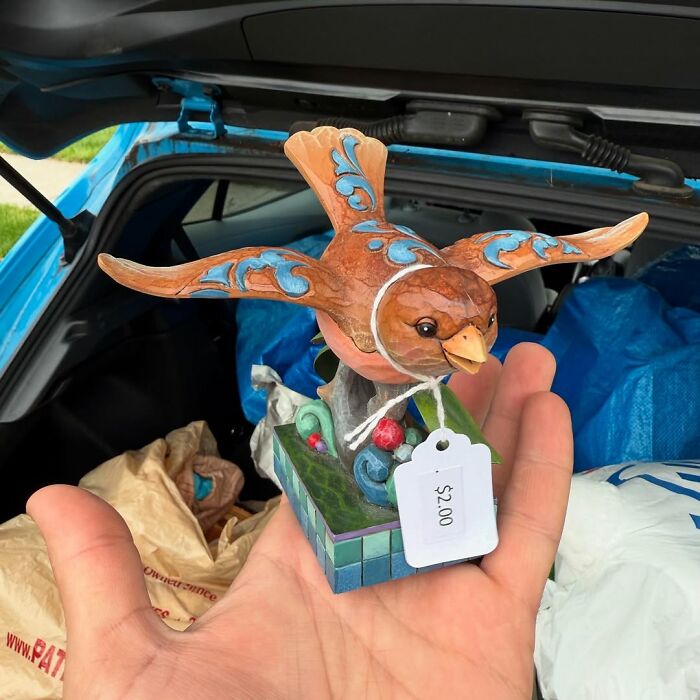 Hand holding a colorful carved bird figurine with a price tag, showcasing cool secondhand finds for collectors.