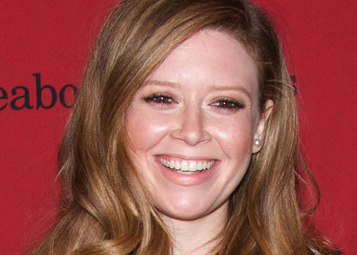 Smiling woman with long hair posing at a red carpet event, illustrating celebrities before fame found them.