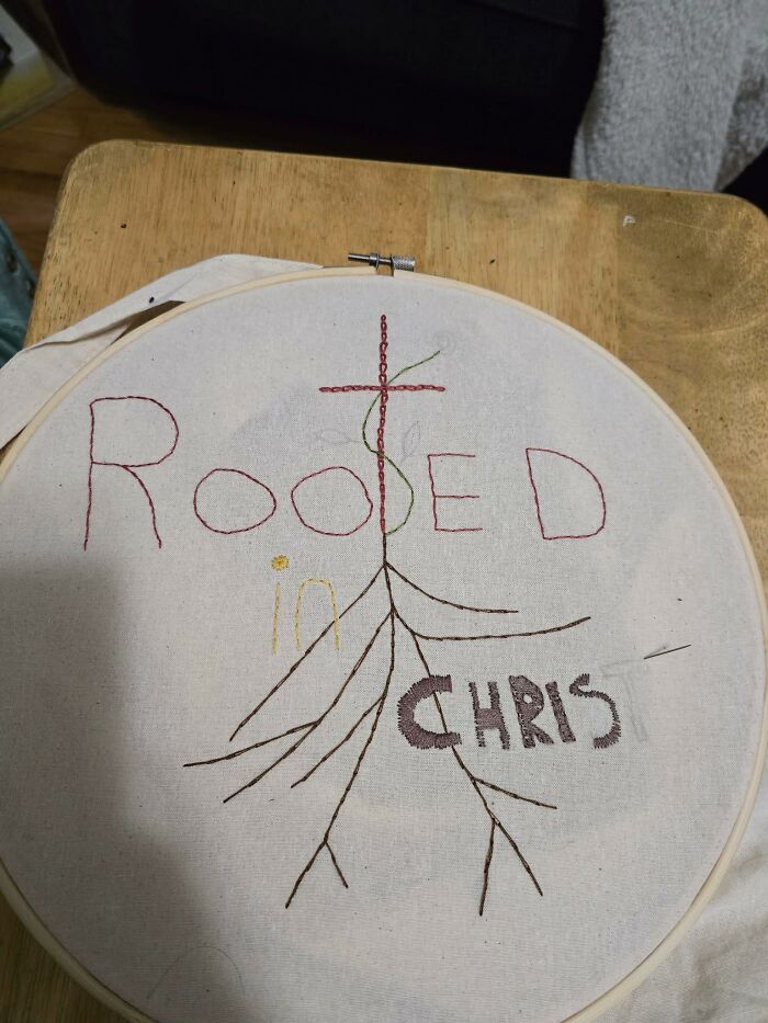 Hand embroidery hoop showing a misspelled DIY project with roots and cross design, a craft shaming example.