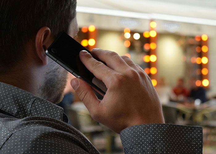 Man in a polka dot shirt talking on phone, symbolizing engagement issues and reasons people called off their engagements.
