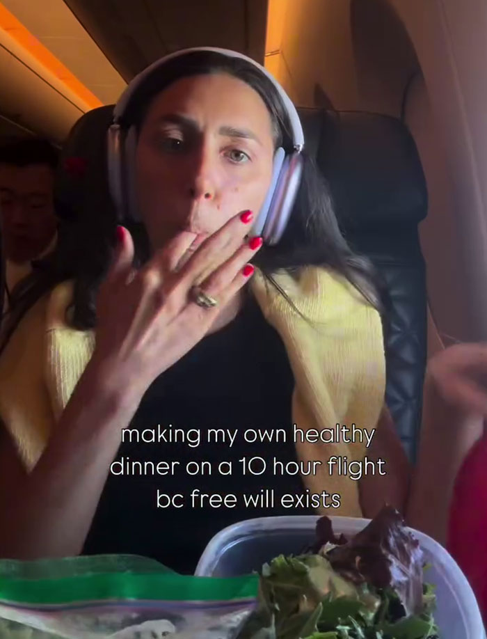 Woman wearing headphones eating a homemade salad mid-flight as a plane passenger on a long-haul flight. Woman wearing headphones eating a homemade salad mid-flight as a plane passenger on a long-haul flight.
