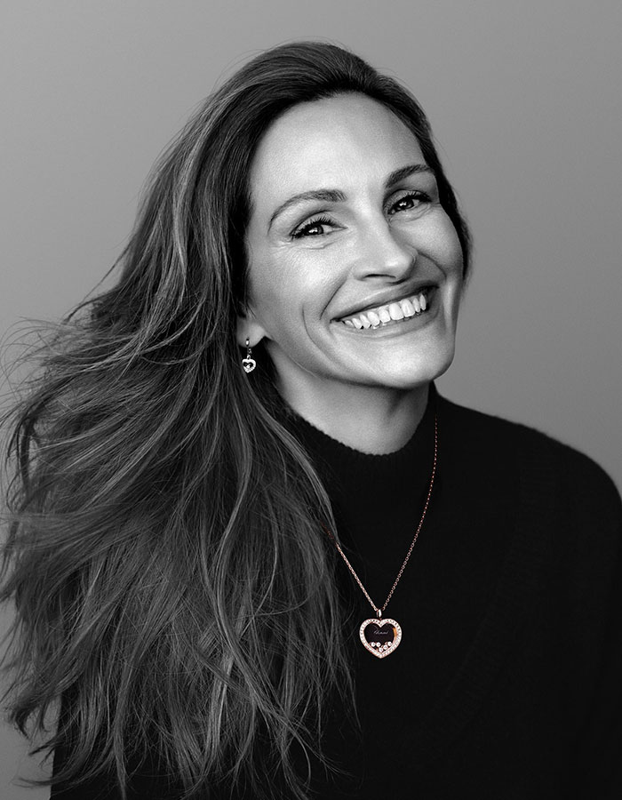 Smiling woman with long hair wearing heart-shaped jewelry, exemplifying celebrities who look way younger than they actually are.