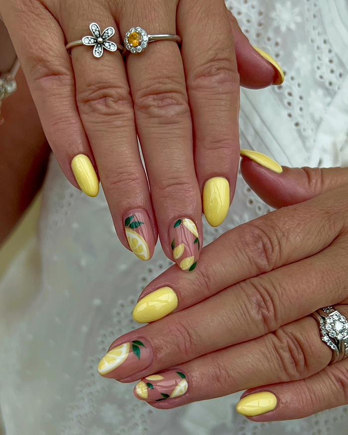 Close-up of hands with yellow summer nails and lemon fruit nail art, highlighting 2025 hottest summer nails trend.