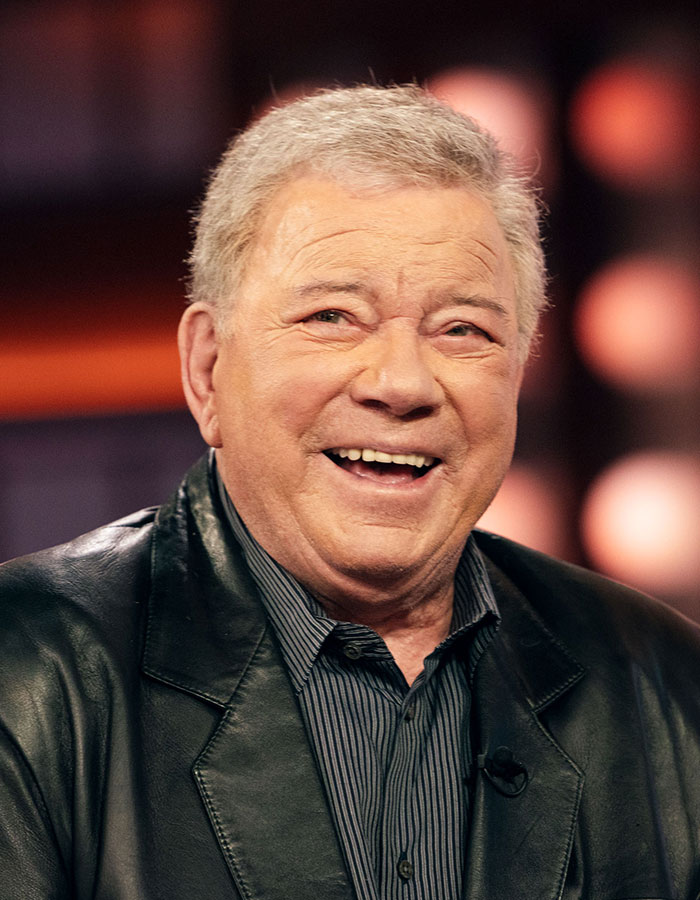 Older celebrity smiling in a leather jacket, showcasing looks that appear way younger than his actual age.