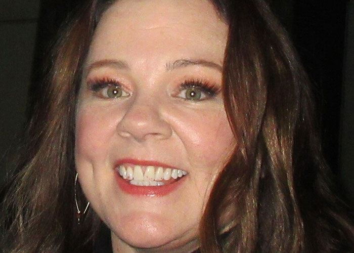 Close-up of a smiling woman showcasing celebrities’ lives before fame in a candid, natural setting with warm lighting.