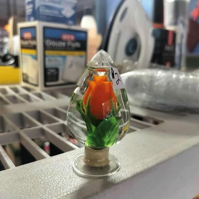 Glass teardrop paperweight with an orange flower inside among cool secondhand finds on a store shelf.