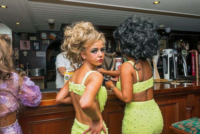 Two women in bright green outfits at a bar, capturing raw and beautiful photos showing life on the margins of modern Ireland.