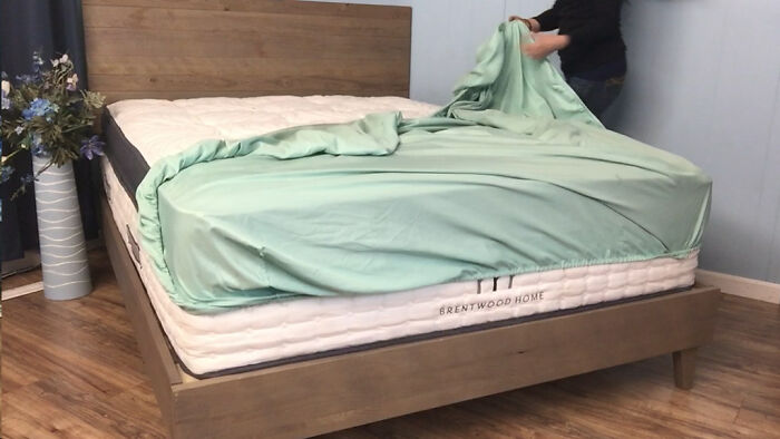 Person making bed with breathable mattress cover, representing comfort and care for women over 42 priorities.