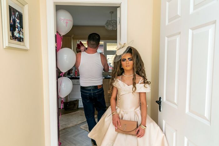 Young girl in a formal dress holding a purse inside a home, illustrating life on the margins of modern Ireland.