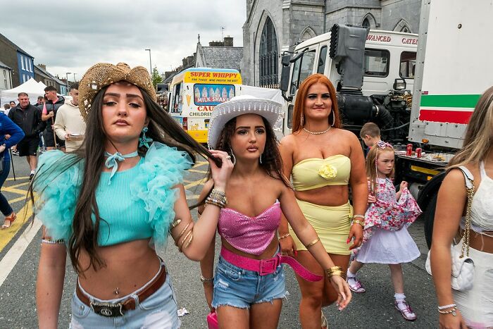 Three young women dressed in vibrant outfits walking on a street, capturing life on the margins of modern Ireland.