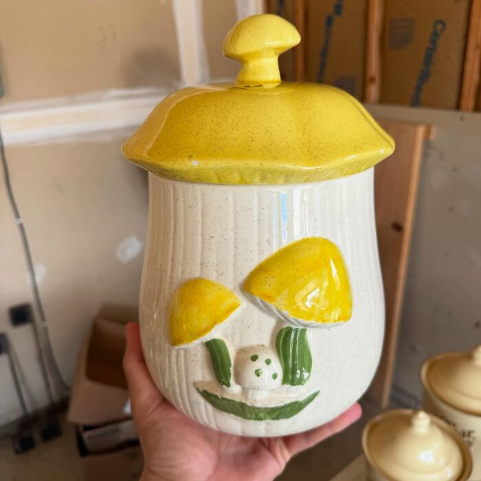 Ceramic jar with yellow mushroom design, a cool secondhand find held in a hand against a workshop background.